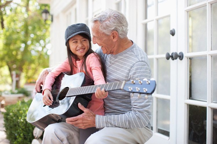 Older Man And Granddaughter Playing Guitar