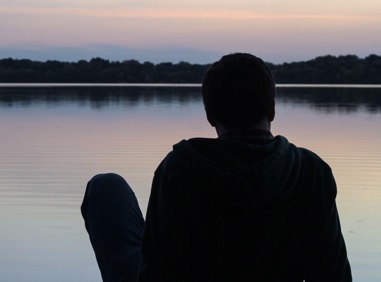 silhouette of a man beside a lake