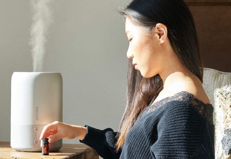 woman holding a small bottle beside a diffuser