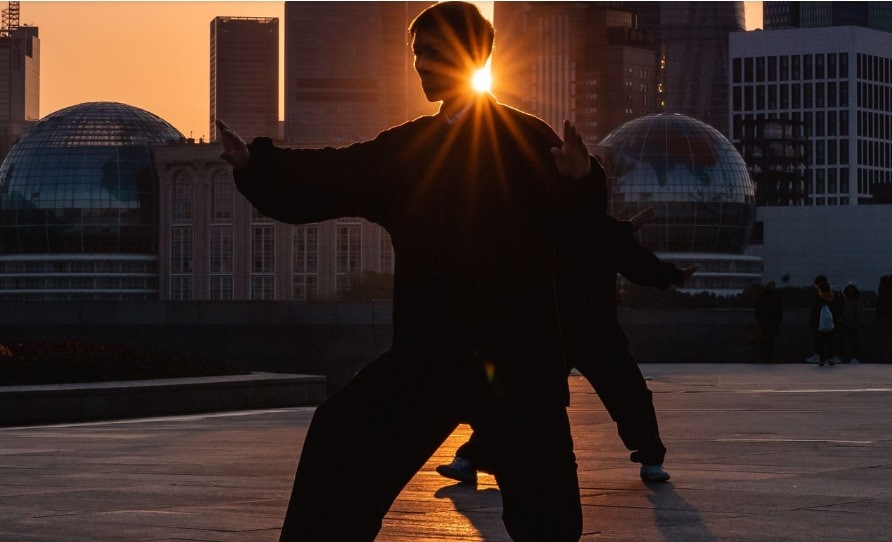 person practicing tai chi in the city with a sunset