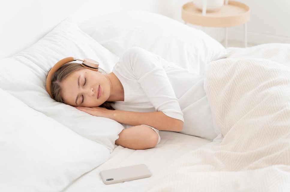 women sleeping with headphones and mobile nearby