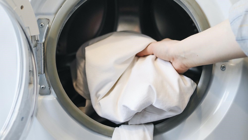 A person placing items in a washing machine