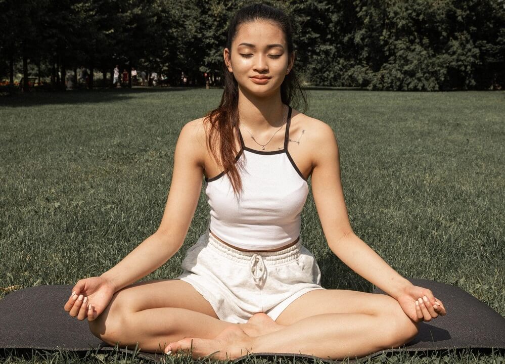 A woman practicing yoga with a lotus pose