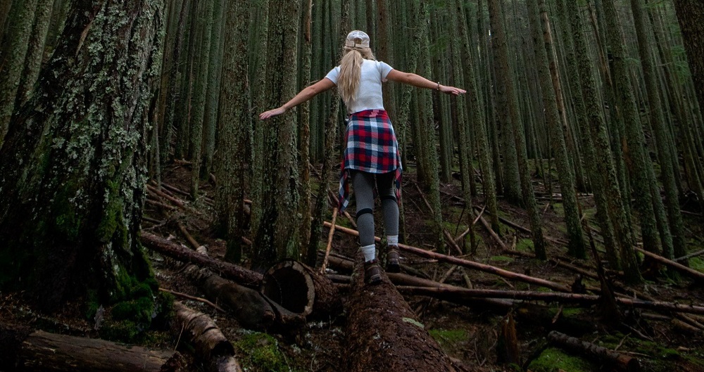 A woman walking on a log in the forest