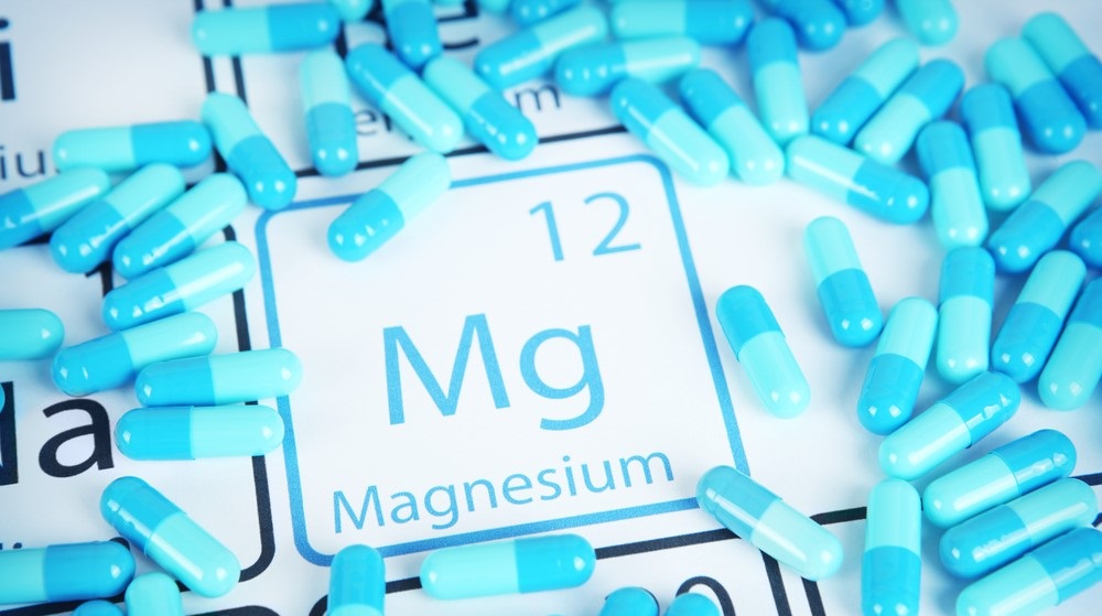 Blue magnesium capsules over periodic table with magnesium element