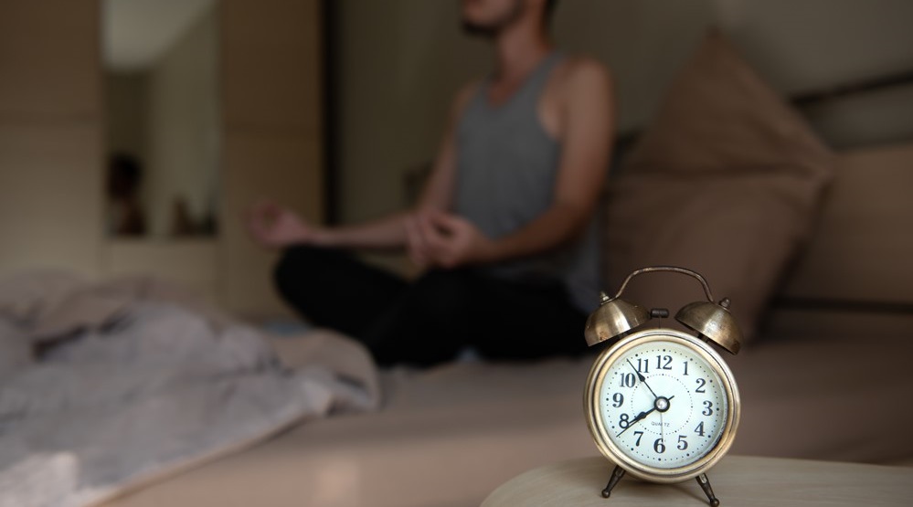 Man meditating in bed before going to sleep