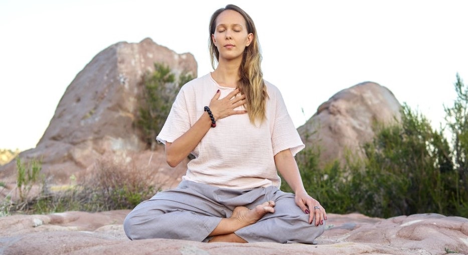 Woman meditating outdoors with one hand on her chest