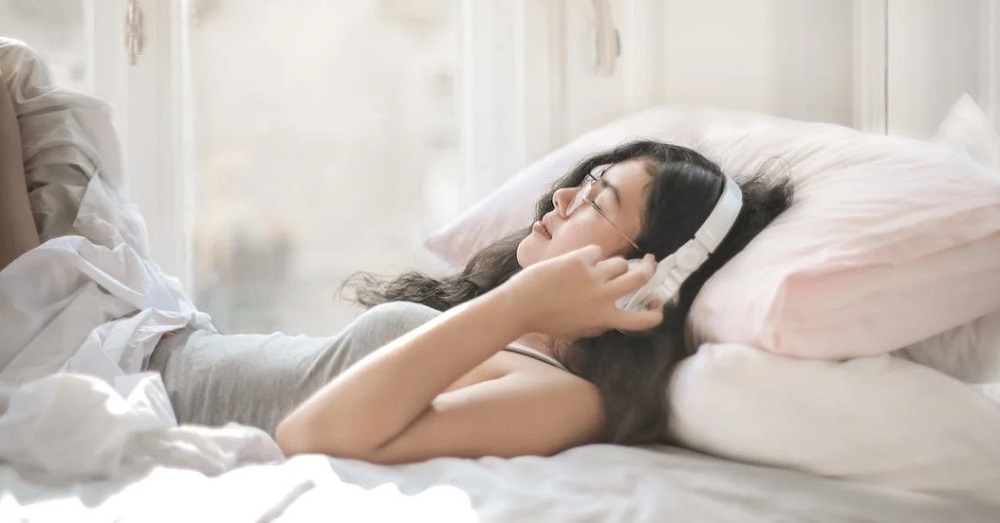 Woman with headphones lying on the bed
