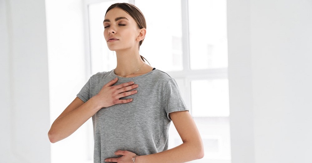 Young woman doing 4-7-8 breathing with hands on her chest and abdomen