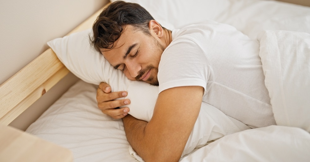 hispanic man hugging pillow lying on bed sleeping at bedroom